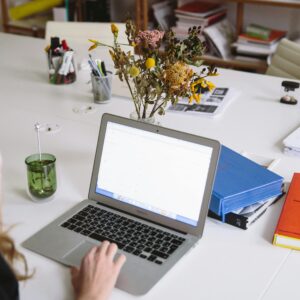 A modern workspace featuring a laptop, dry flowers, and office supplies, ideal for remote work.